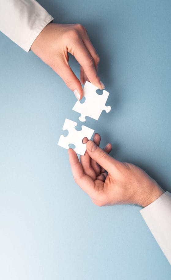 Two people fitting together pieces of a jigsaw puzzle